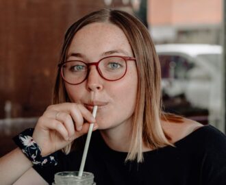 young female wearing red glasses sips lemonade after she opens her first checking account SheeksFreaks Financial Skills for Young Adults