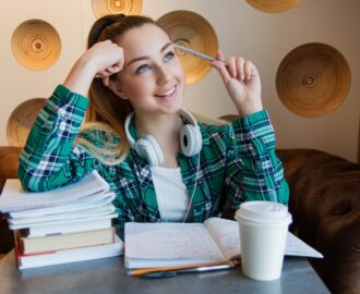 teenage female Cayla with a stack of books near by, considers whether or not to purchase a vehile