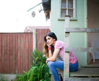 young woman Raj sits outside her porch content with her financial decisions SheeksFreaks Financial Skills for Young Adults